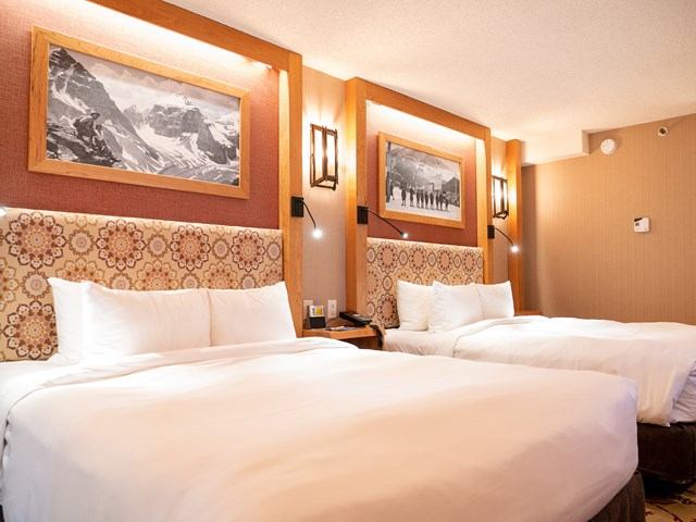 Warm  room with two beds and mountain-themed decor.