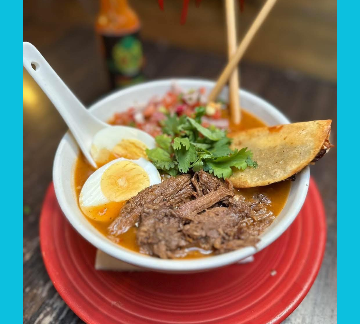Bowl of soup with shredded meat, boiled egg, cilantro and folded tortilla.