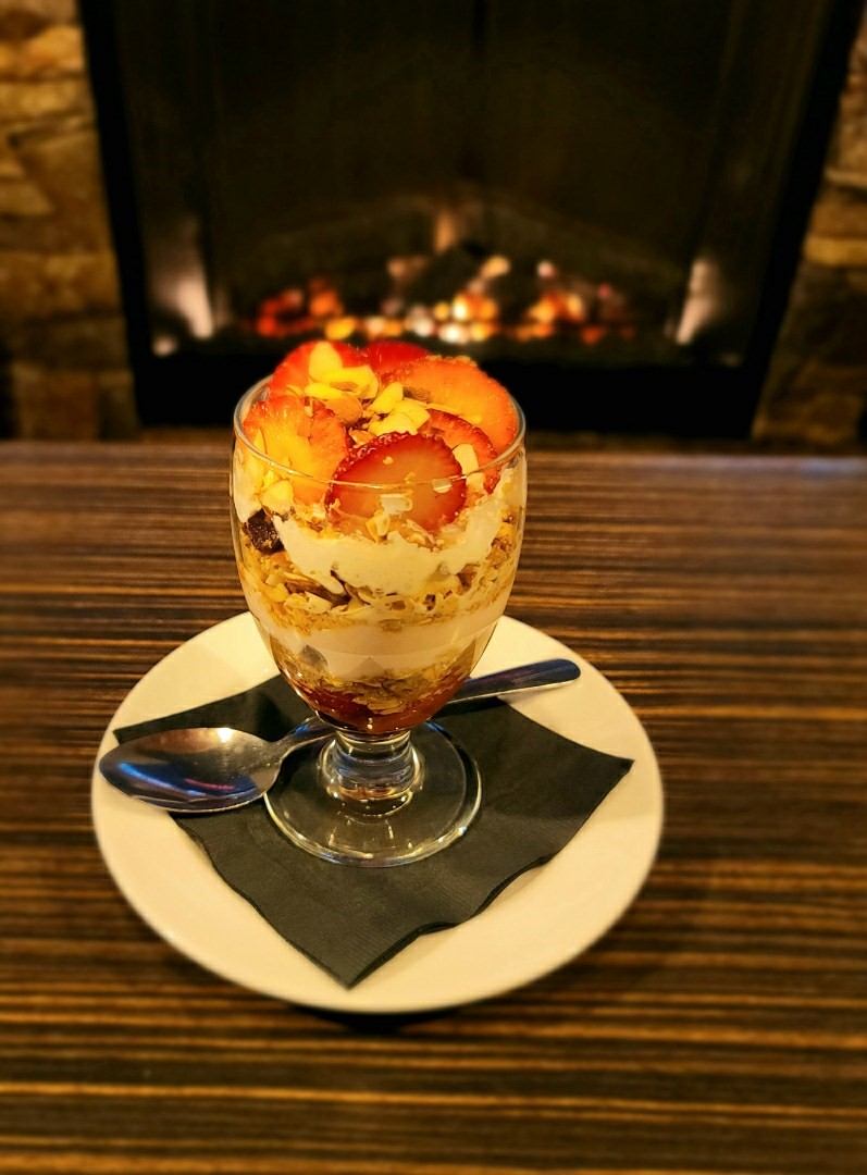 Strawberry parfait in tall glass by cozy fireplace at Jax Grill and Lounge.