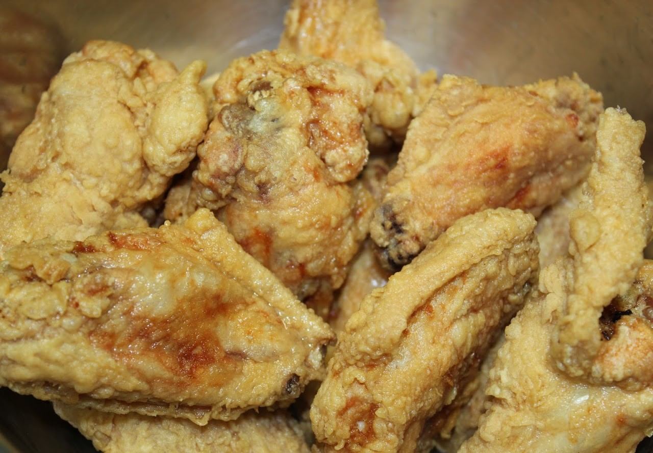 Close-up of a pile of golden-brown fried chicken wings with a crunchy coating.
