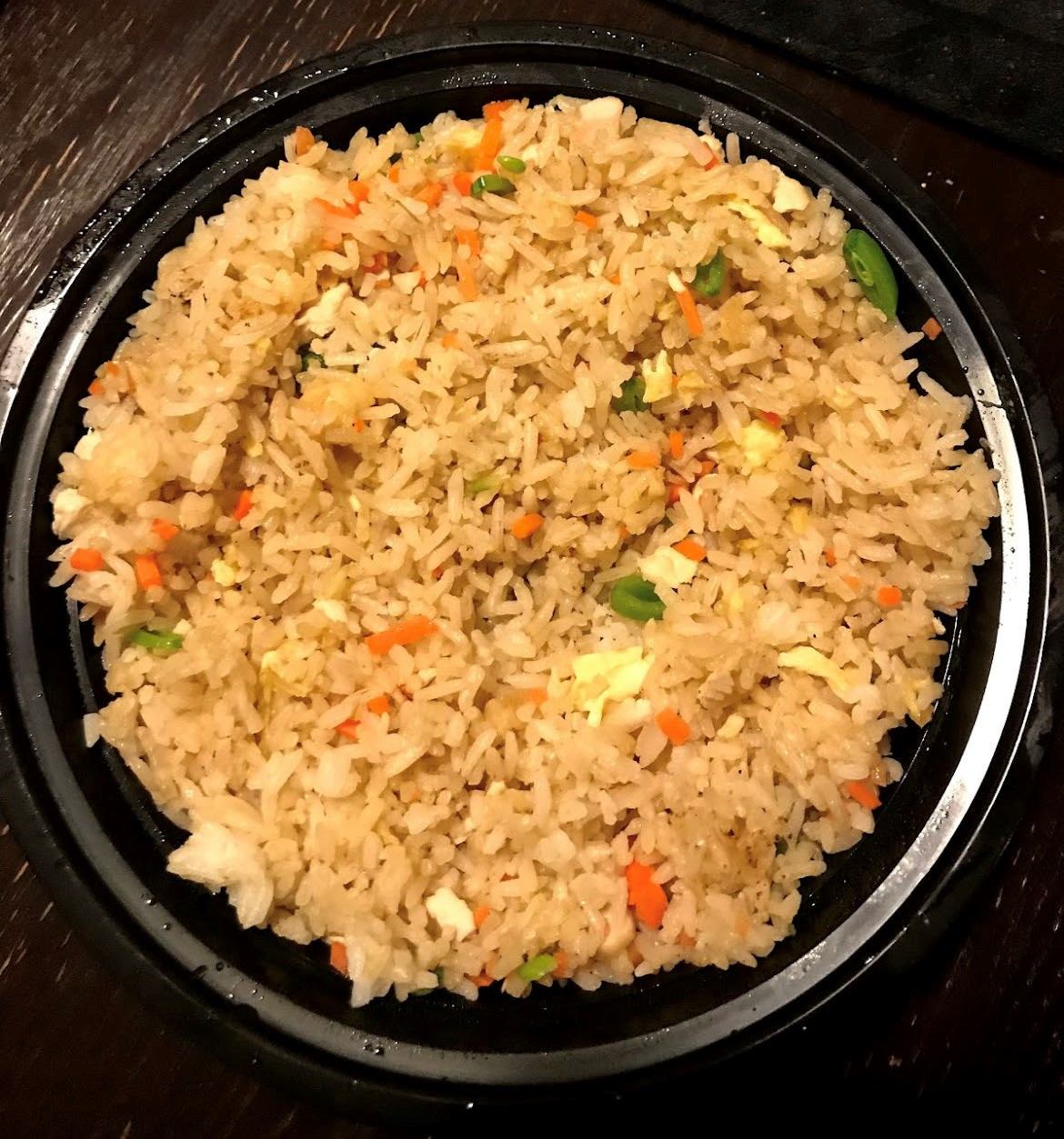 Ninja Noodle dish of fried rice with peas, carrots, and scrambled egg in a black bowl.