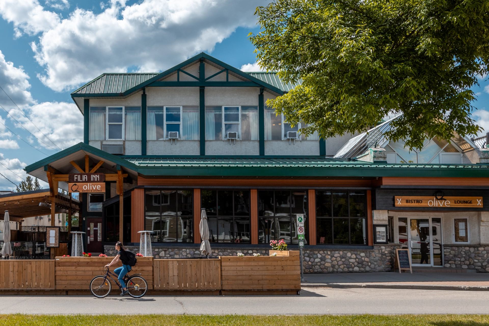 Filia Inn with green roof, outdoor seating, and a cyclist passing by.