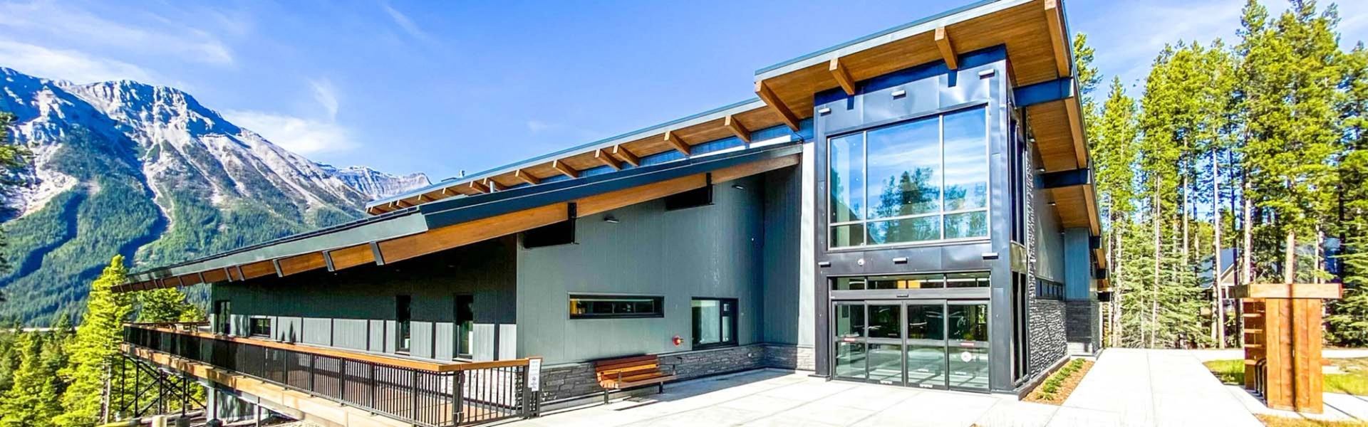 Modern lodge building with forest and mountain backdrop.