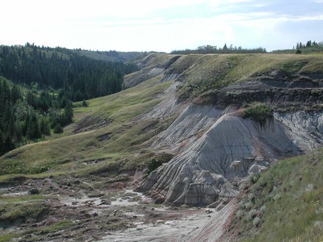 Eroded hills and rocky terrain with sparse vegetation and layered rock formations.
