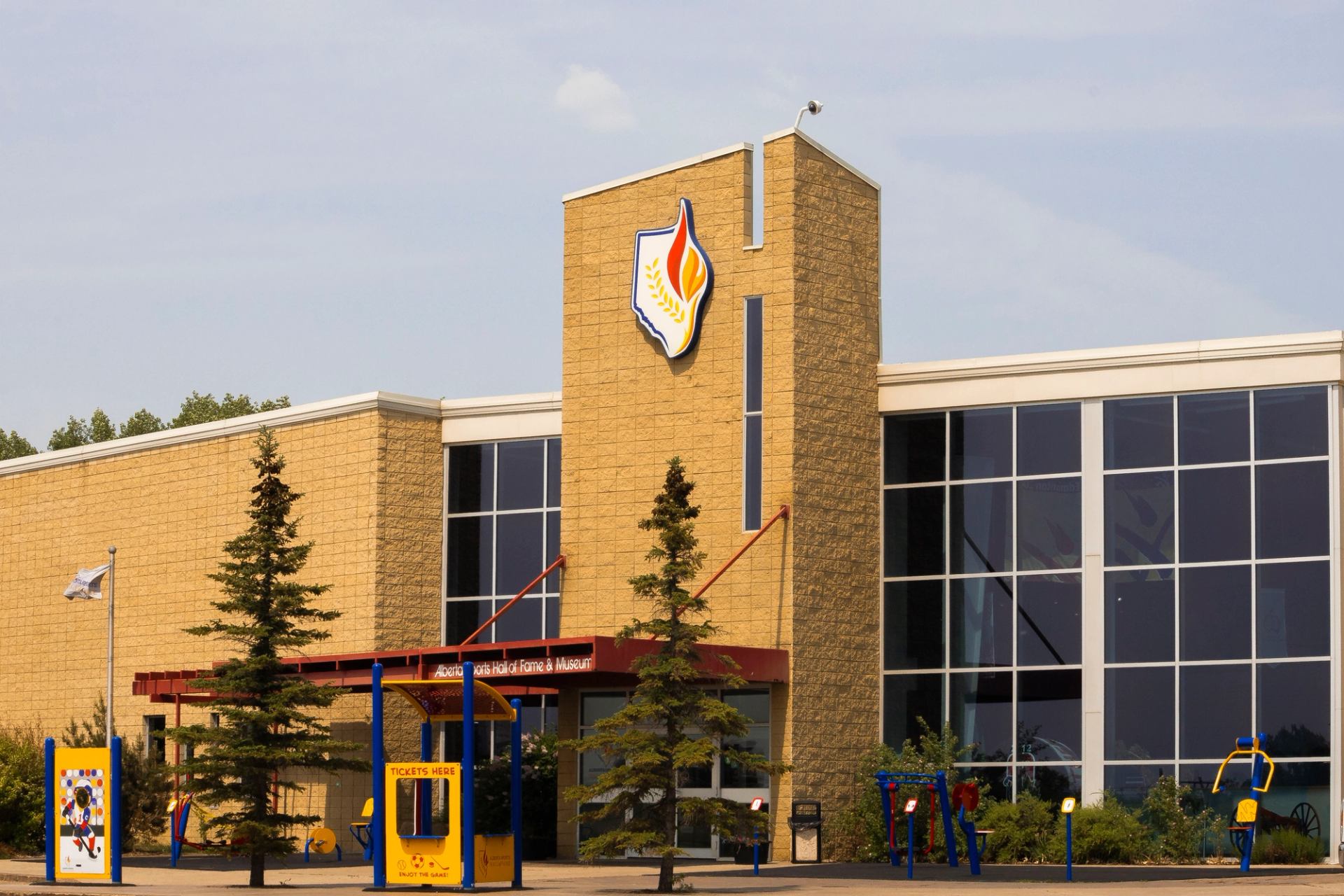 Exterior of Alberta Sports Hall of Fame and Museum with flame logo and playground equipment.