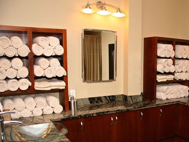 Shelves stacked with rolled white towels beside a mirror in the spa area.