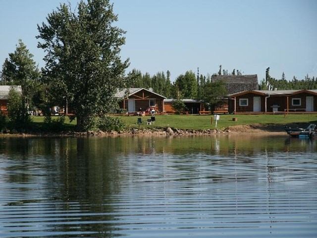 Cabins and trees along the shore of Christina Lake with calm water in front.