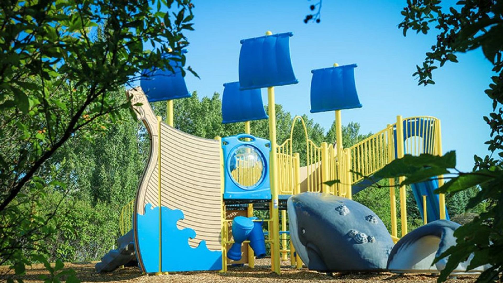 Colorful playground with slides and climbing features surrounded by trees at Eastview Park Campground.