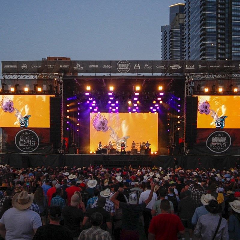 Outdoor Roundup Musicfest stage with band performing for large crowd in cowboy hats.
