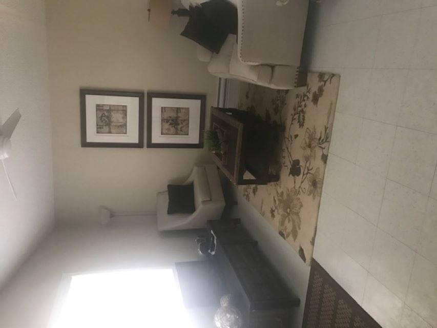 Living room corner with sofa, framed pictures, and floral curtains on a window wall.