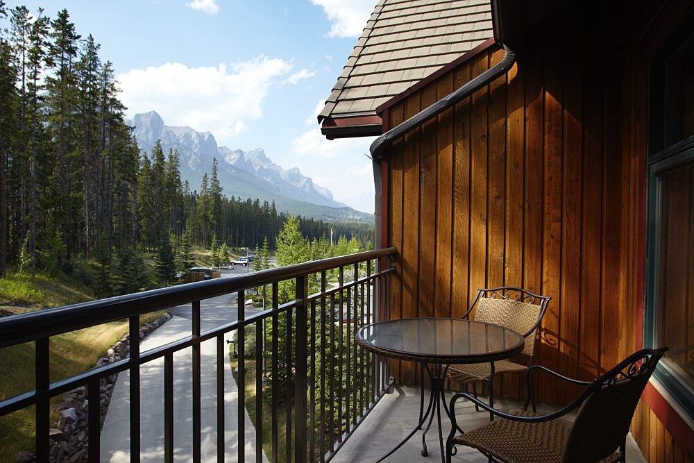 Balcony with table and chairs overlooking mountains and forest