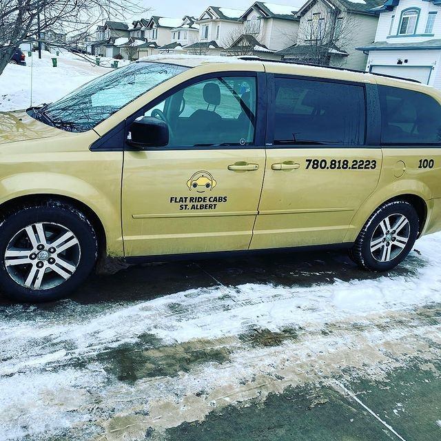 Yellow Xpress Ride Cabs minivan with phone number, parked in snow-covered residential area.
