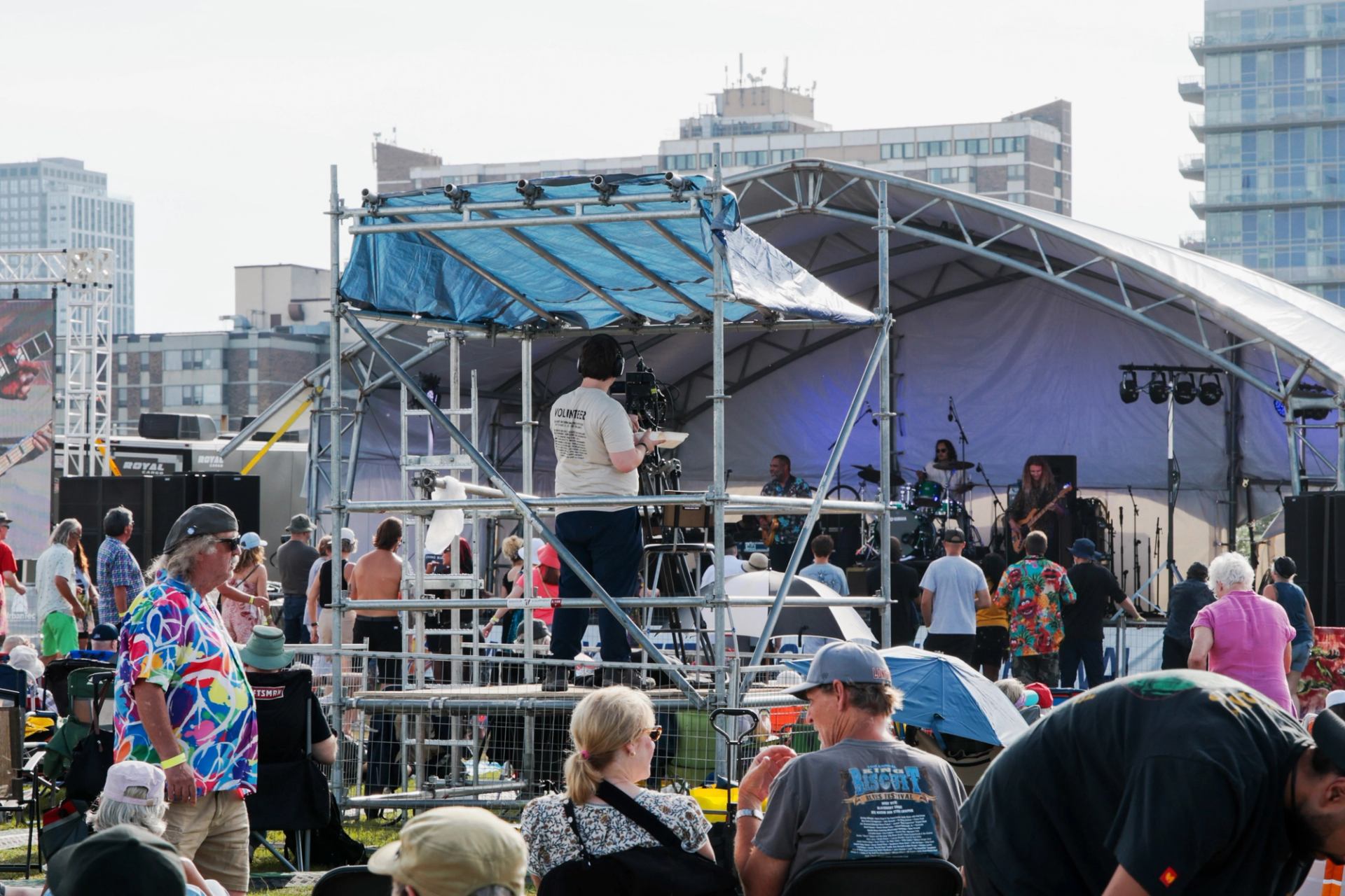 Festival audience and camera crew filming musicians on an outdoor stage