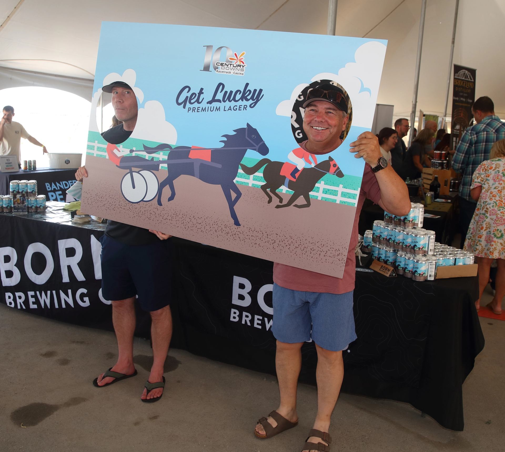 Two people pose with horse racing cutout at Libations Fest