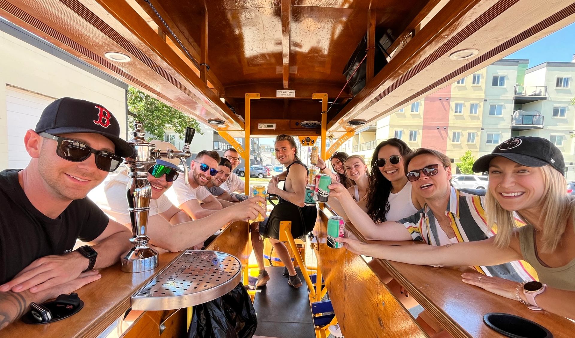 Friends raising drinks inside a Pedal Pub bike while cruising through downtown Edmonton.