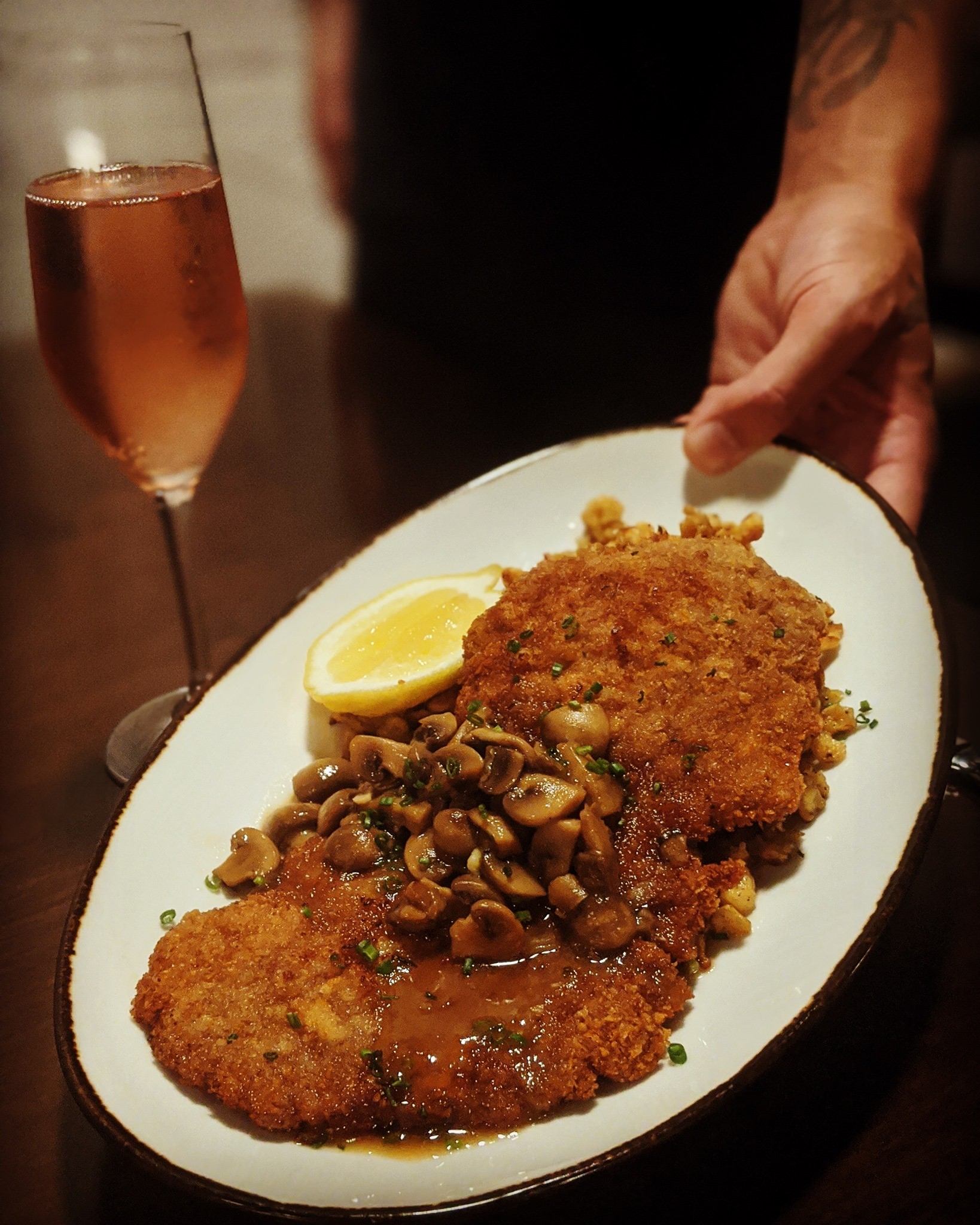 Crispy cutlets topped with sauce beside pink drink in restaurant setting.