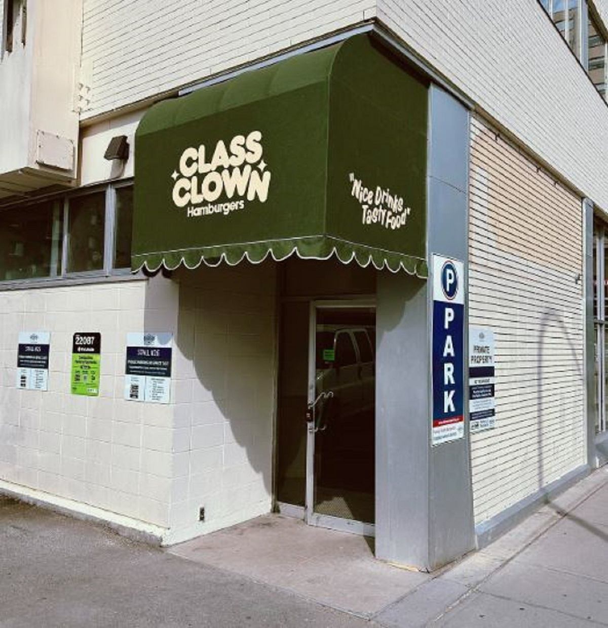 Exterior of Class Clown Hamburgers with a green awning over the door.