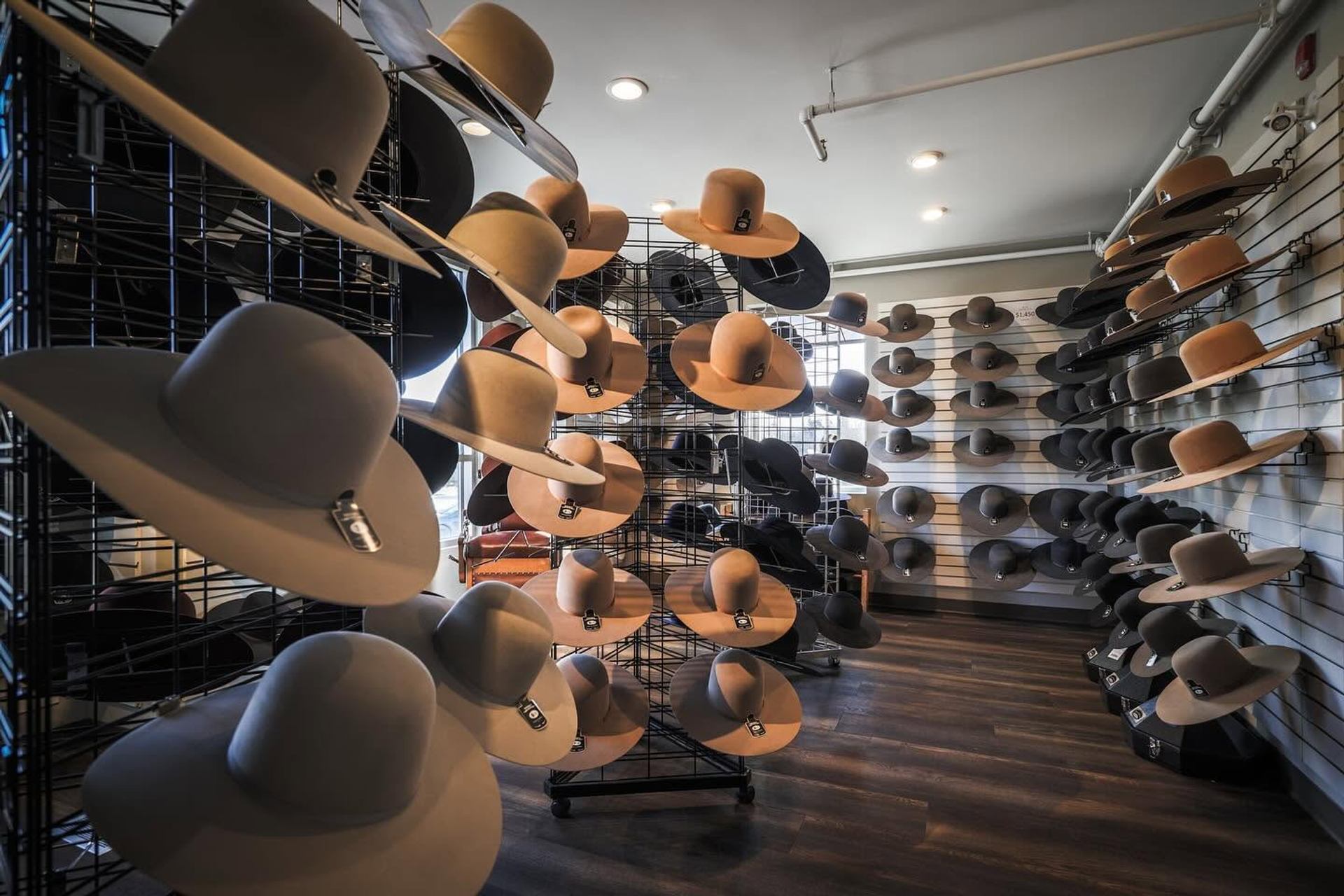 Wall displays and racks filled with wide-brimmed felt hats in a retail shop.