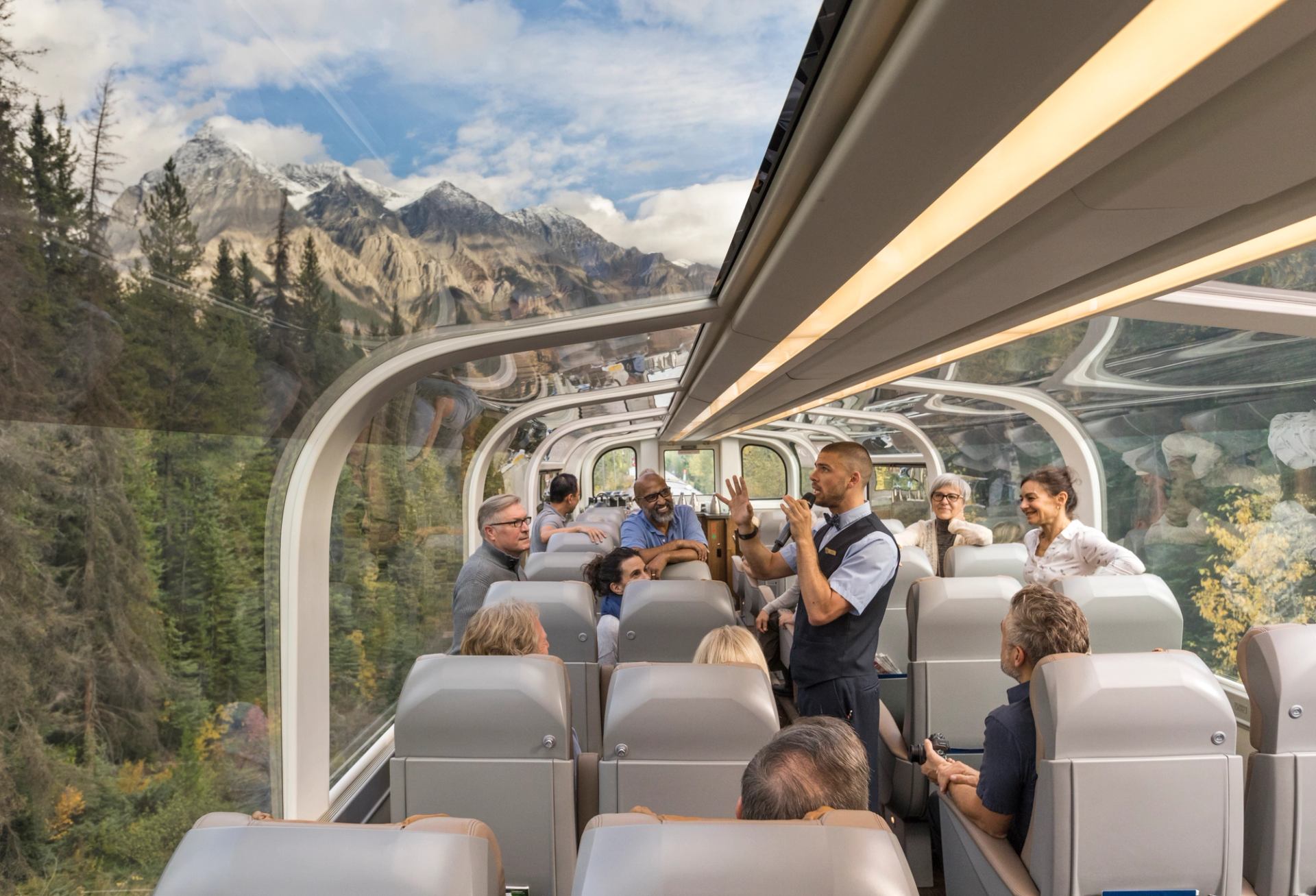 Interior of a Rocky Mountaineer glass‑dome coach with wide seats and panoramic mountain views.