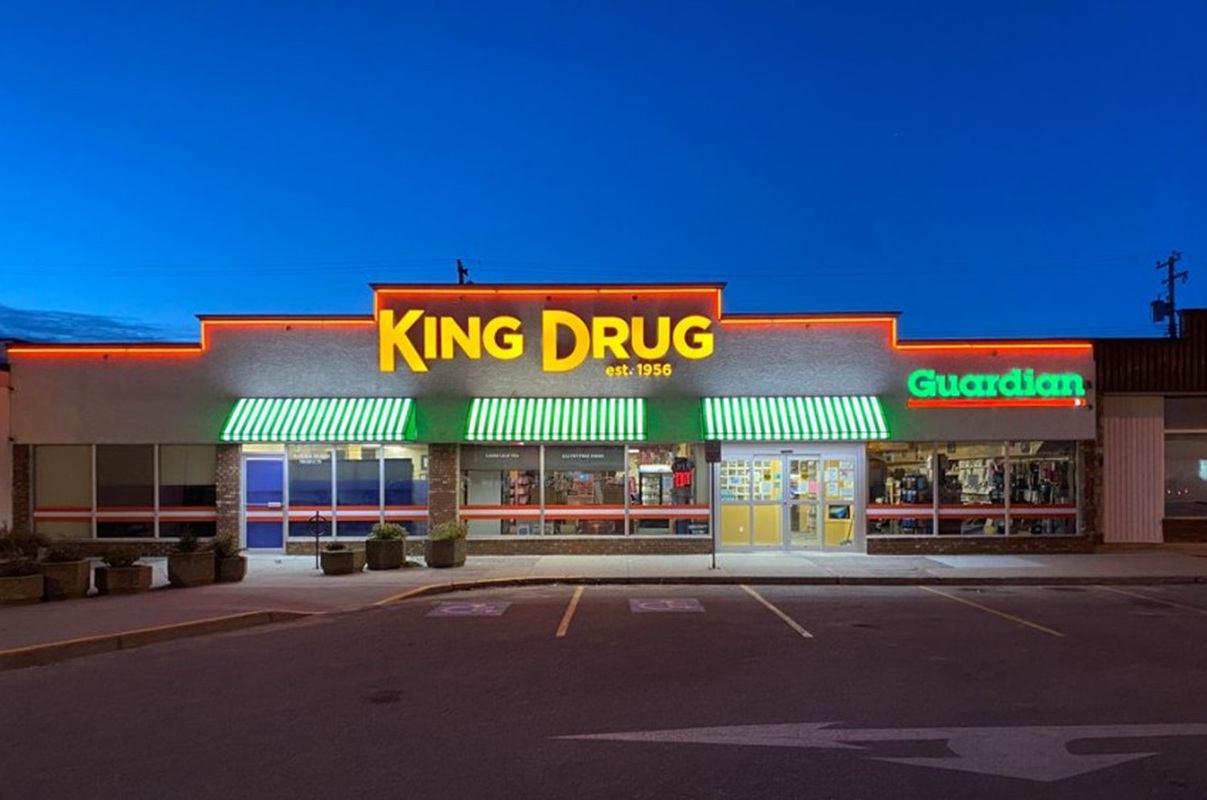 King Drug storefront lit up at night with neon signage and striped awnings