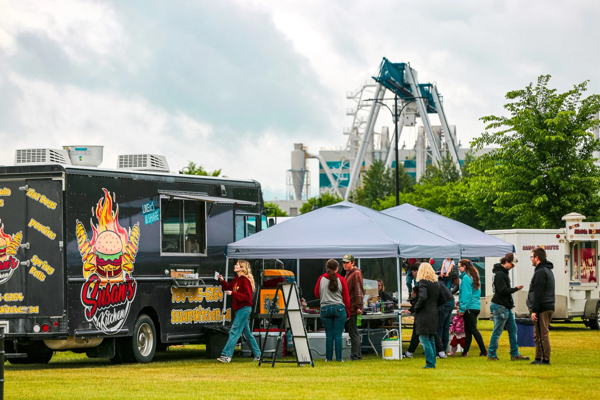 People gathered at food trucks and tents at an outdoor festival.