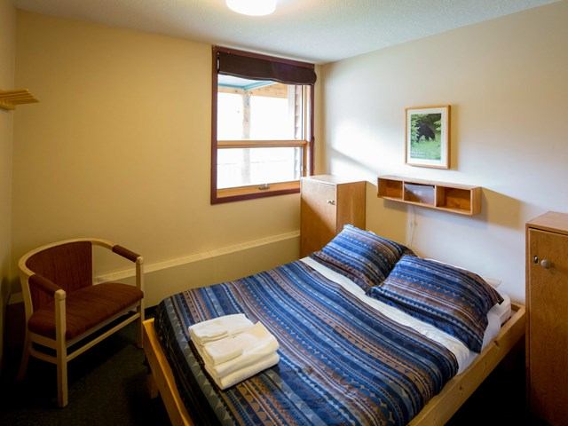 Cozy bedroom with striped bedding, towels, and natural light from a window.