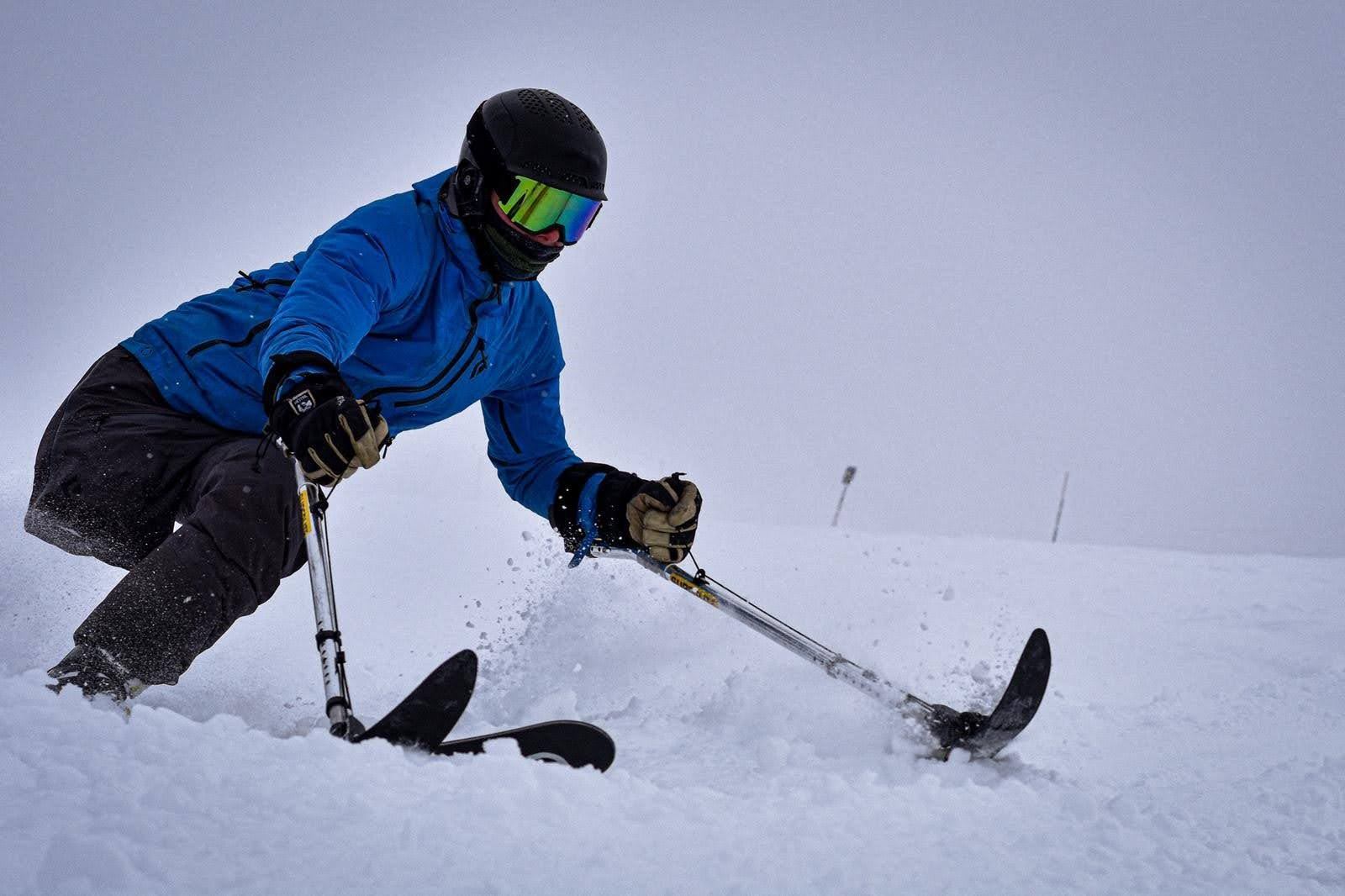 Skier using adaptive equipment on snowy slope.