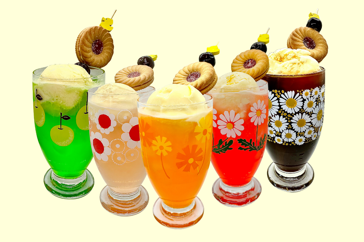 Colourful ice cream floats in floral glasses topped with cookies and cherries.