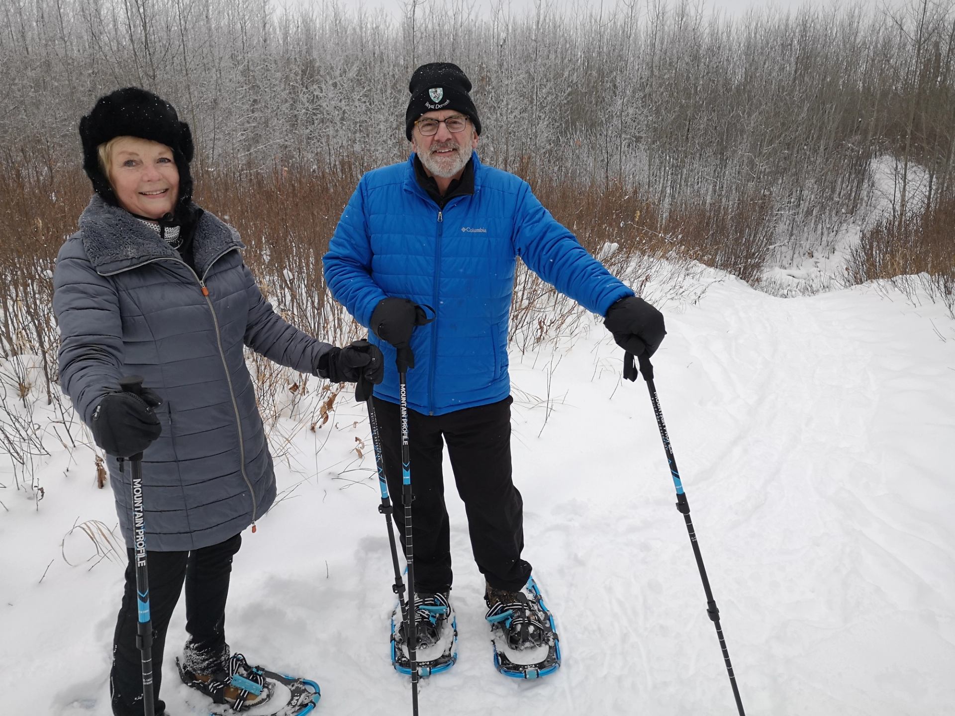 A couple snowshoeing along a trail.