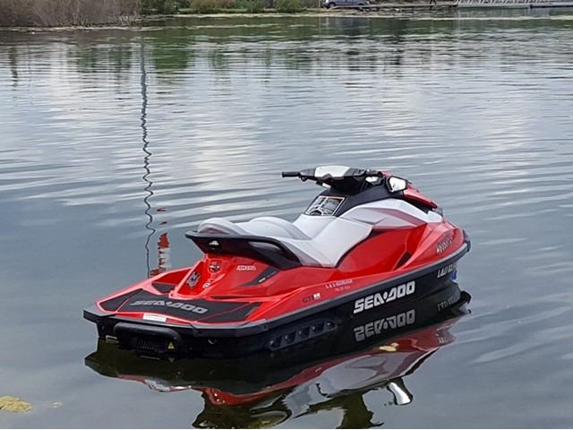 Red and black Sea-Doo jet ski floating on calm water.