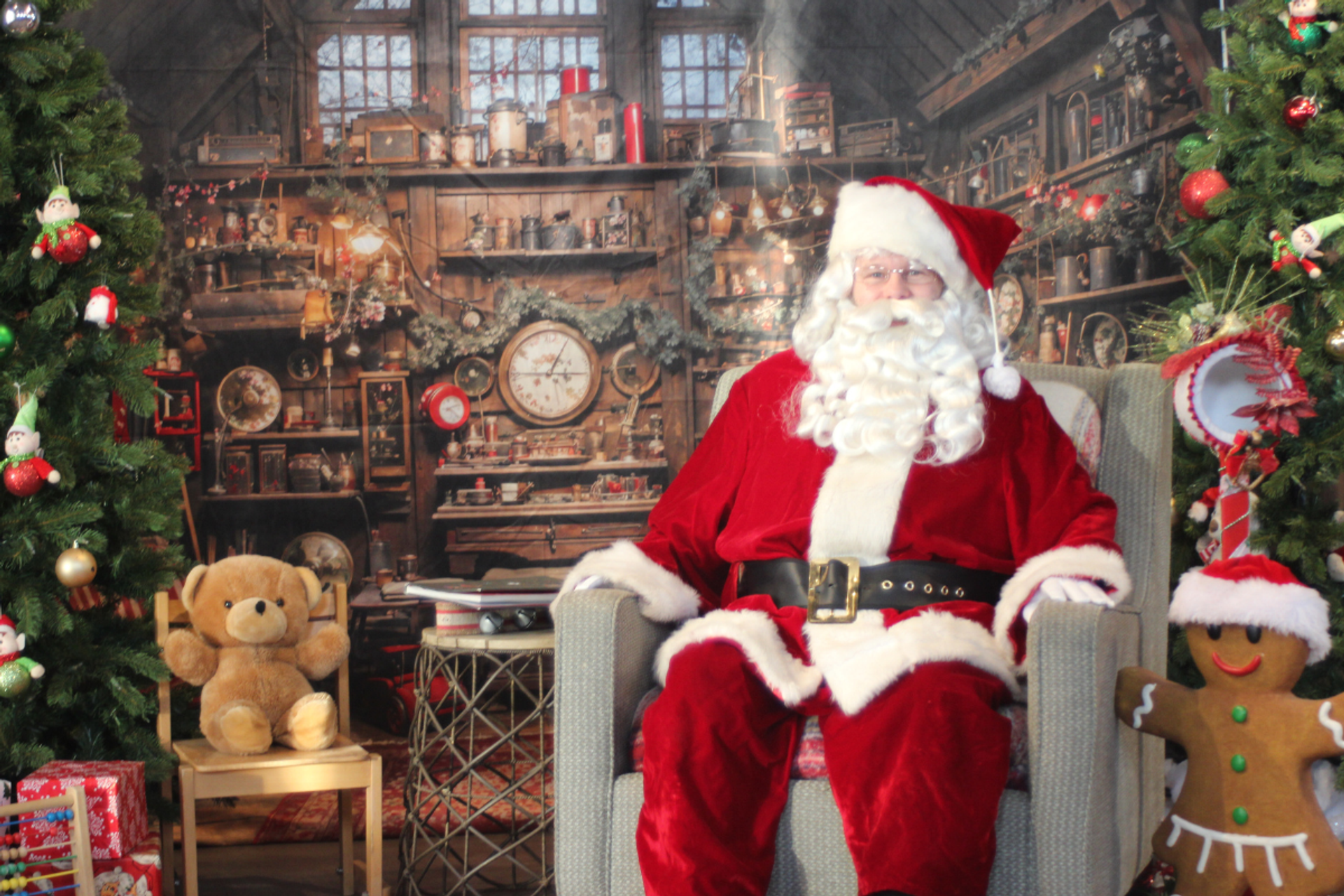 Santa sits in a festive room at Granary Road, surrounded by Christmas trees and toys.