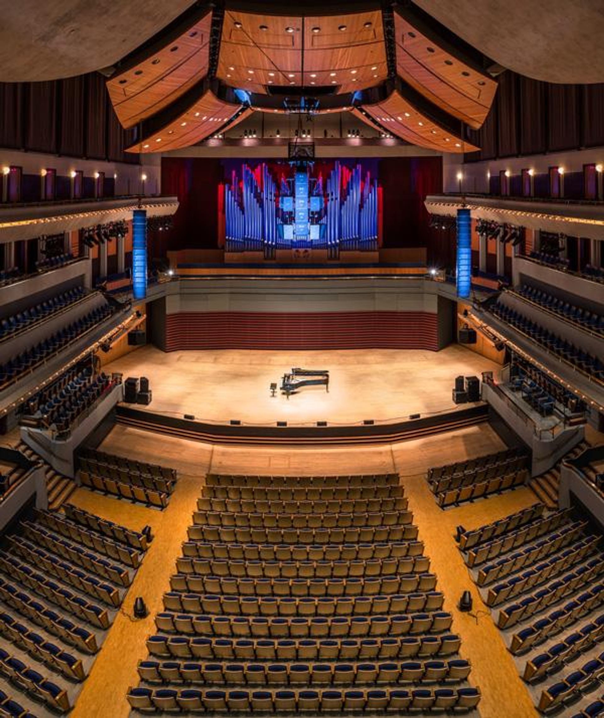 Concert hall with tiered seating, a grand piano and pipe organ above the stage.