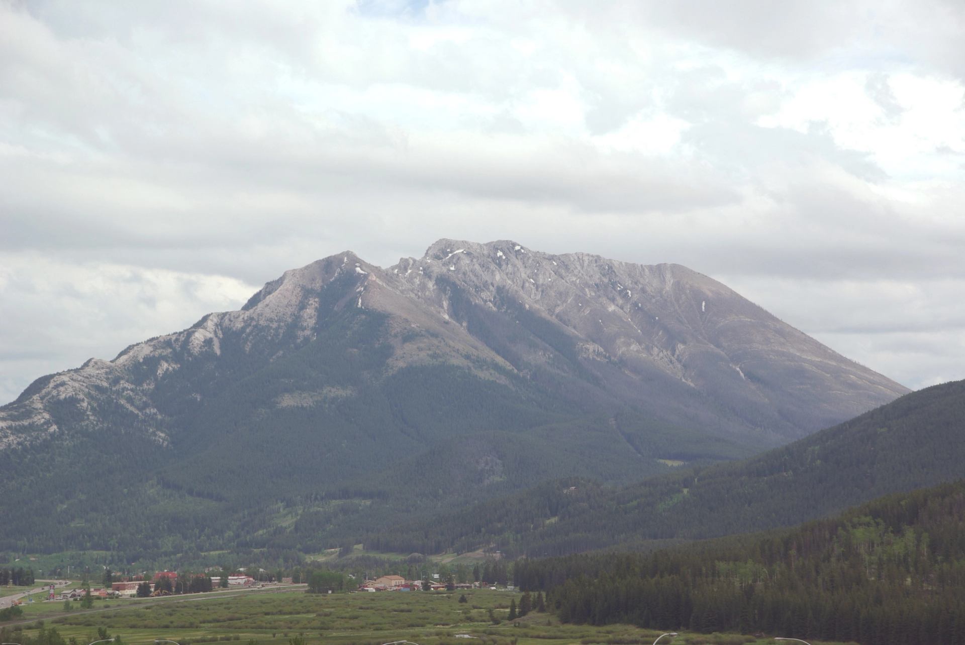 Majestic mountain range with green forest under cloudy sky