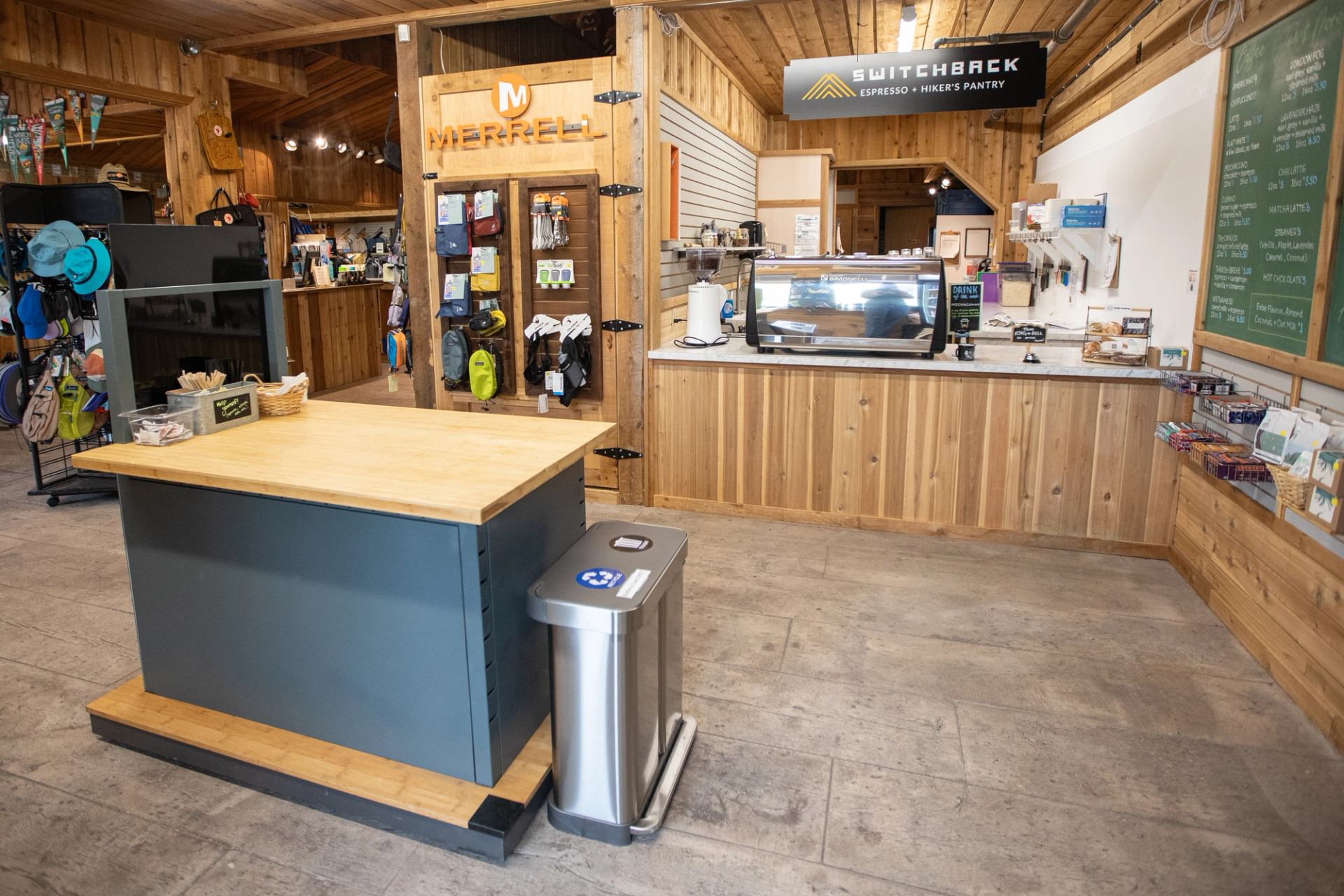 Wood-panelled café and gear shop interior with Merrell display and Switchback counter.