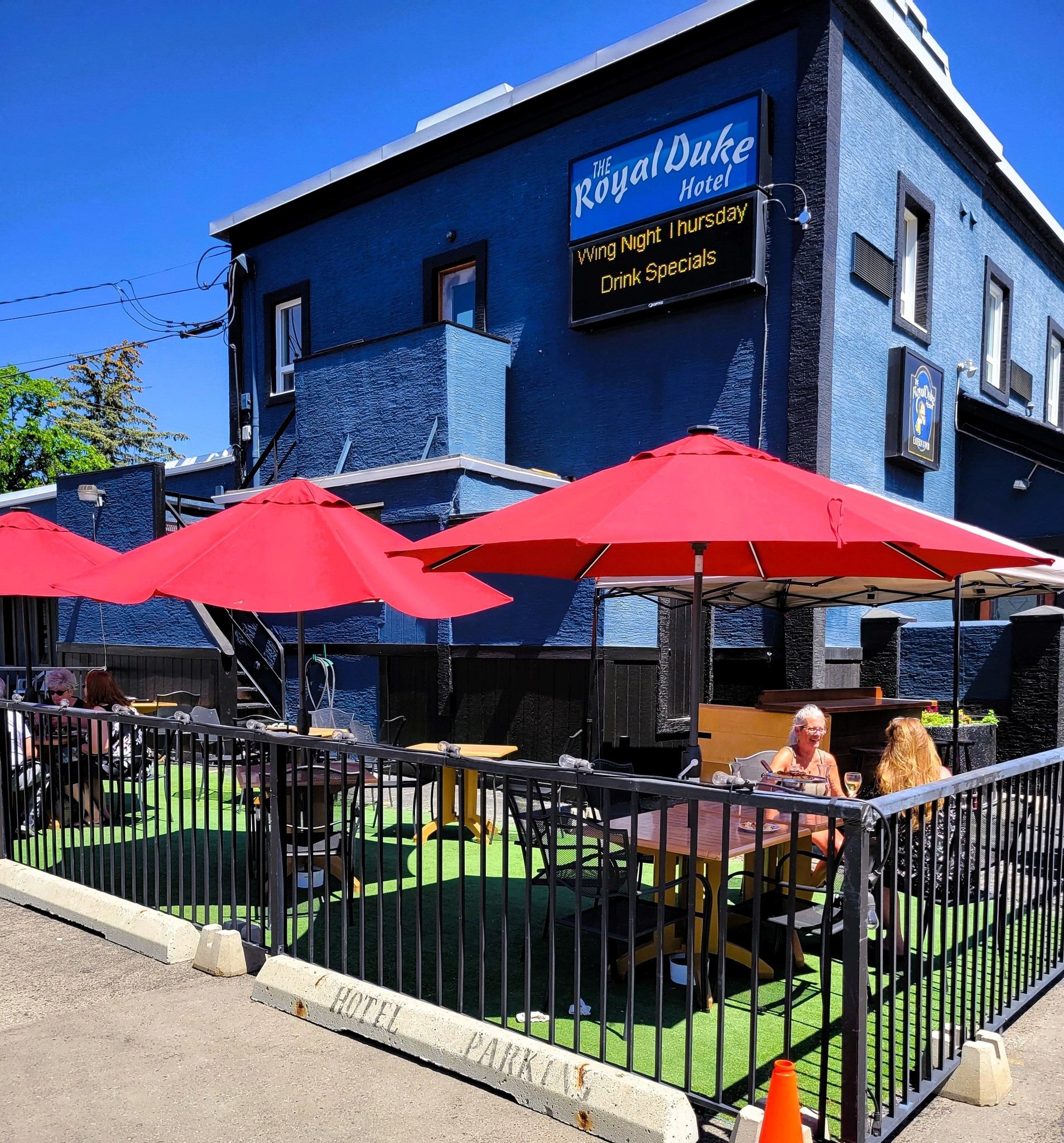 Outdoor patio with red umbrellas and seating at The Royal Duke Hotel.