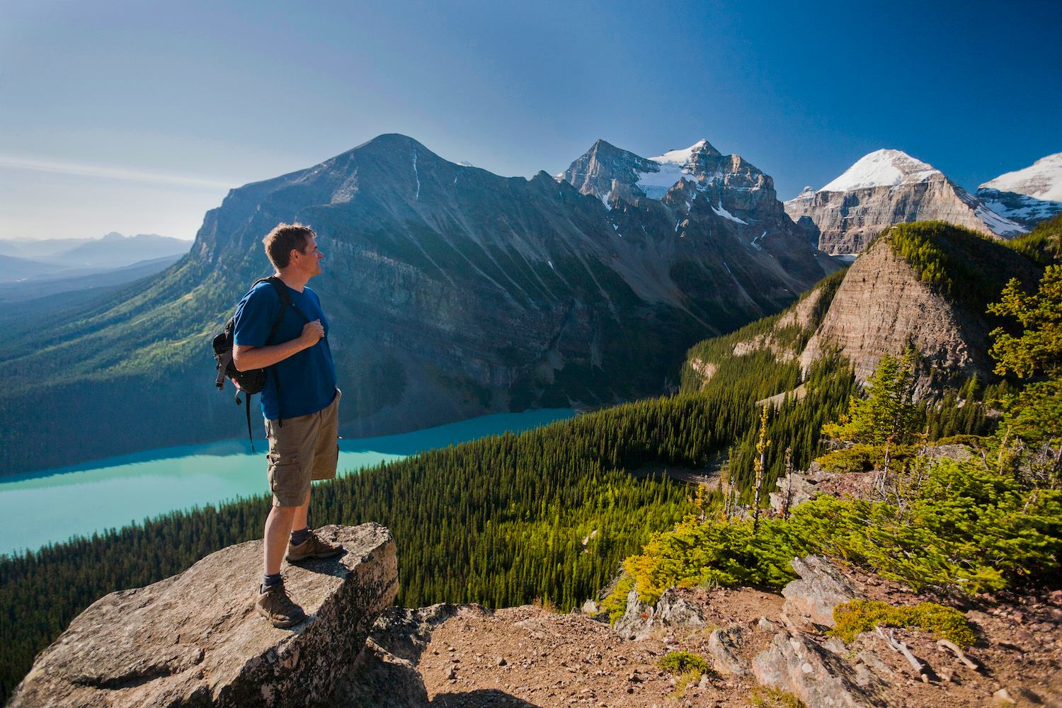 A man taking in the view of Lake Louise while stood on a rock.