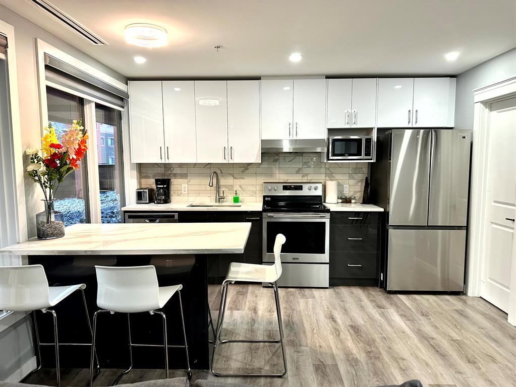 Contemporary kitchen with white cabinets, stainless appliances, and a breakfast bar.