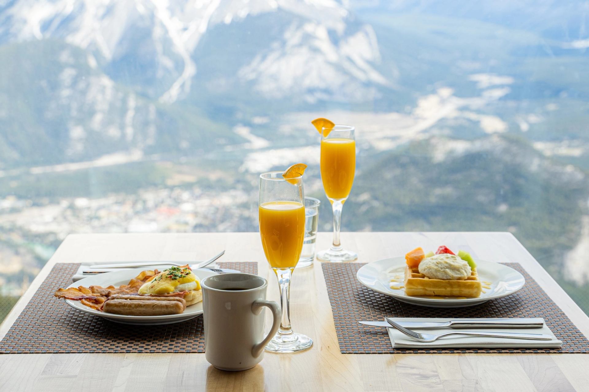 Breakfast plates and drinks on a table overlooking a scenic mountain landscape.