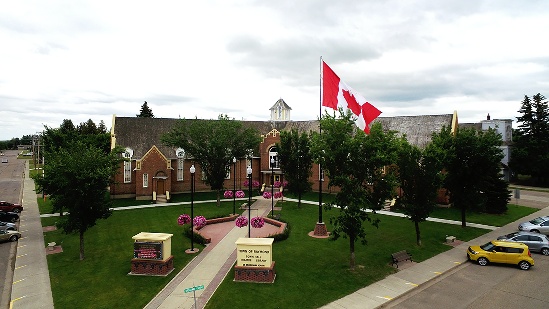 Aerial view of brick theatre building with Canadian flag and landscaped entrance.