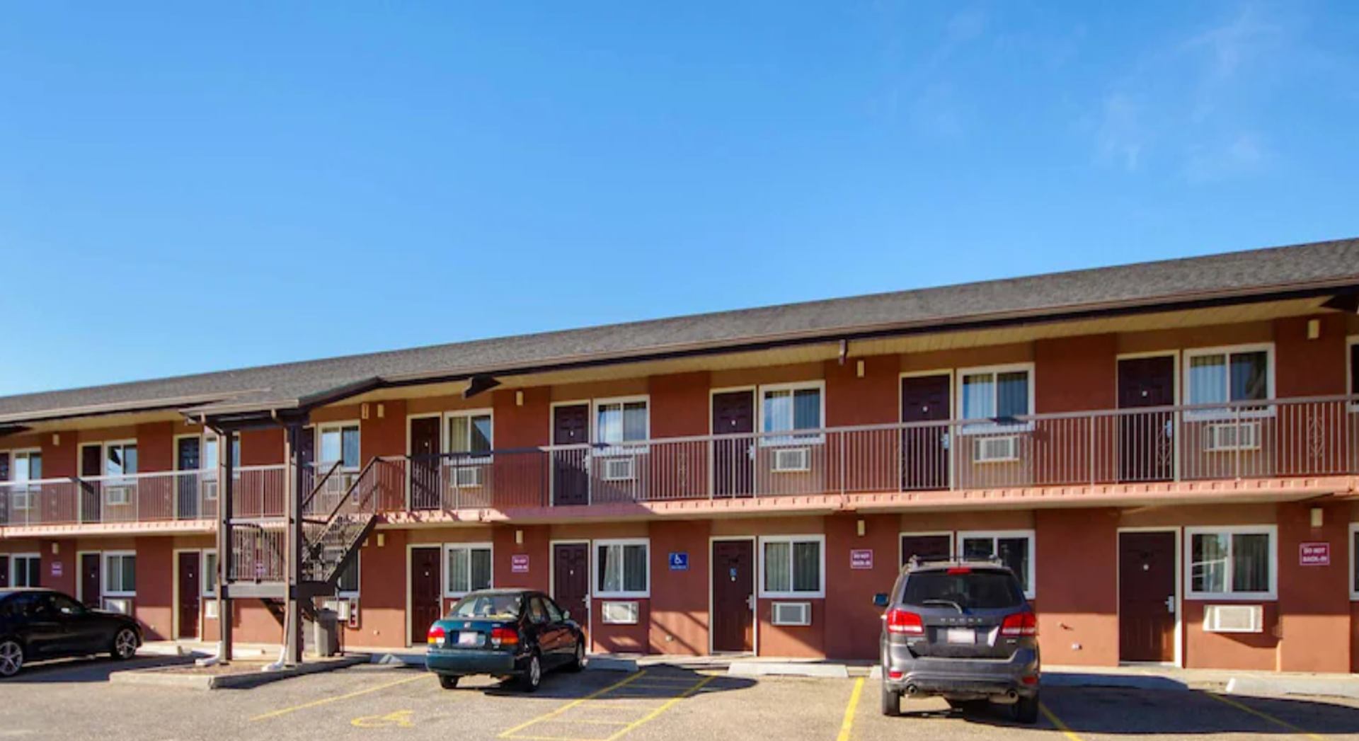 A two-story Motel 6 building overlooks a parking area with guest rooms and exterior walkways.