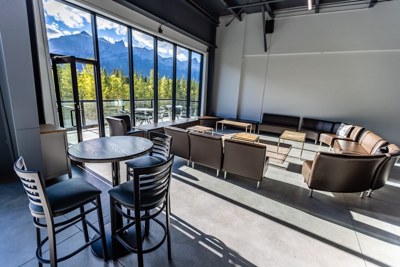 Lounge area with sofas and tall windows showing forest and mountain scenery