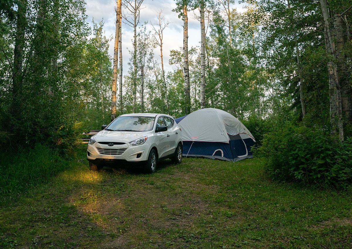A tent and an SUV set up in a campsite.