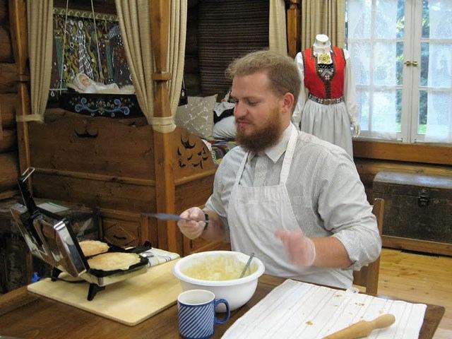 Person making waffles in rustic kitchen with wooden walls and traditional decor.