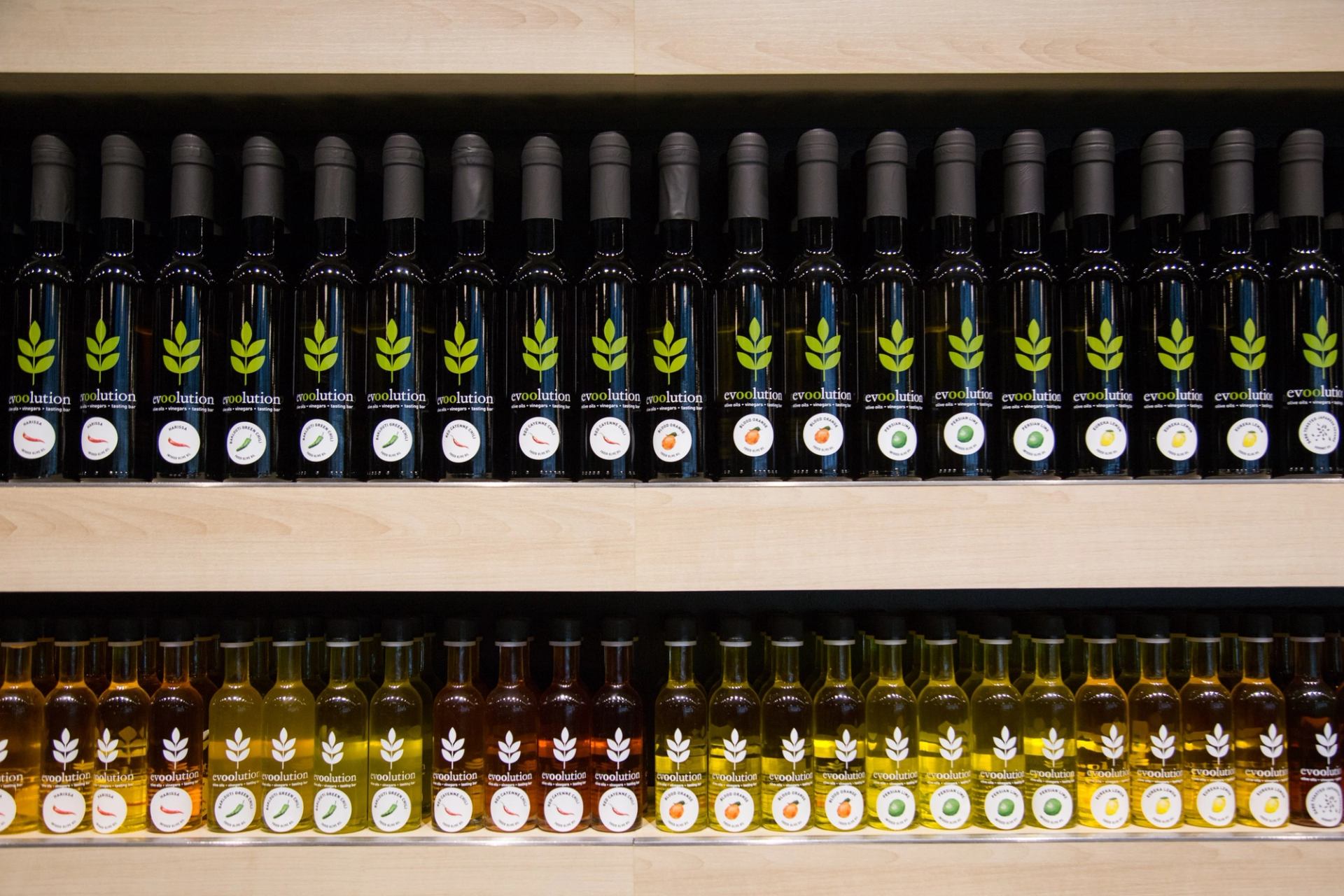 Shelves stocked with assorted olive oil bottles organized by color and type.