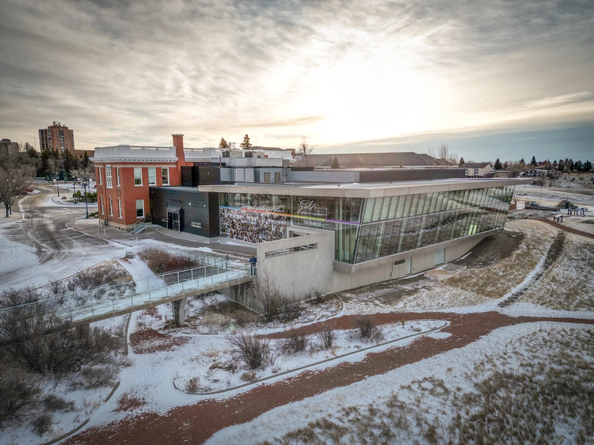 Exterior view of Galt Museum & Archives with modern glass design and snowy landscape at sunset.