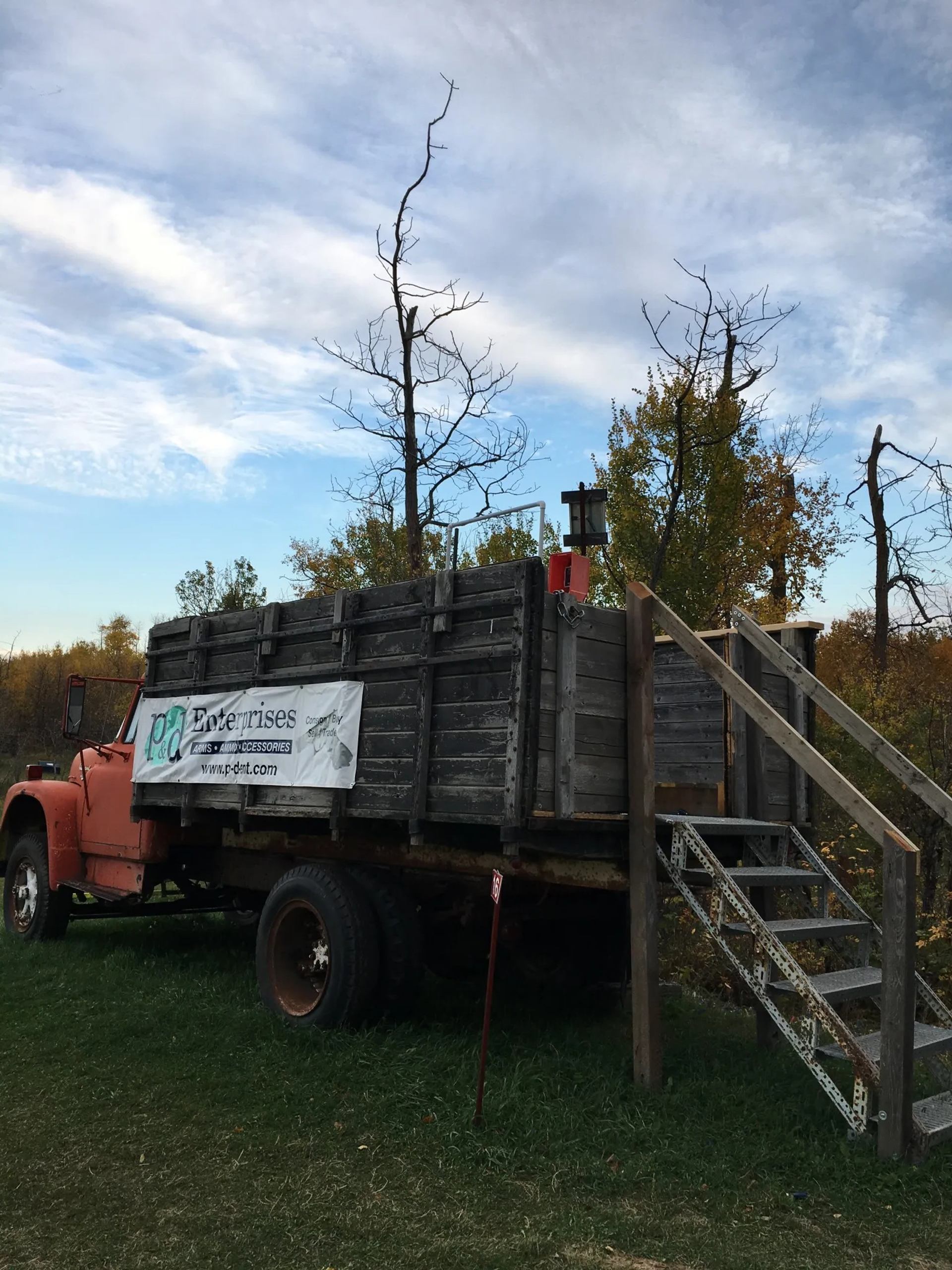 Old red farm truck with wooden box, attached stairs and PD Enterprises banner.