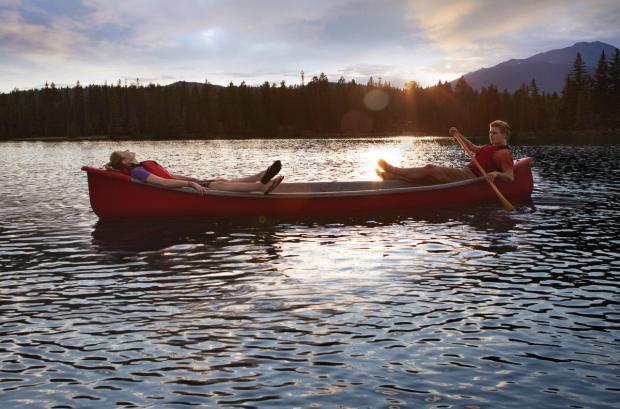 Couple relaxing in canoe on Lac Beauvert in Jasper National Park.