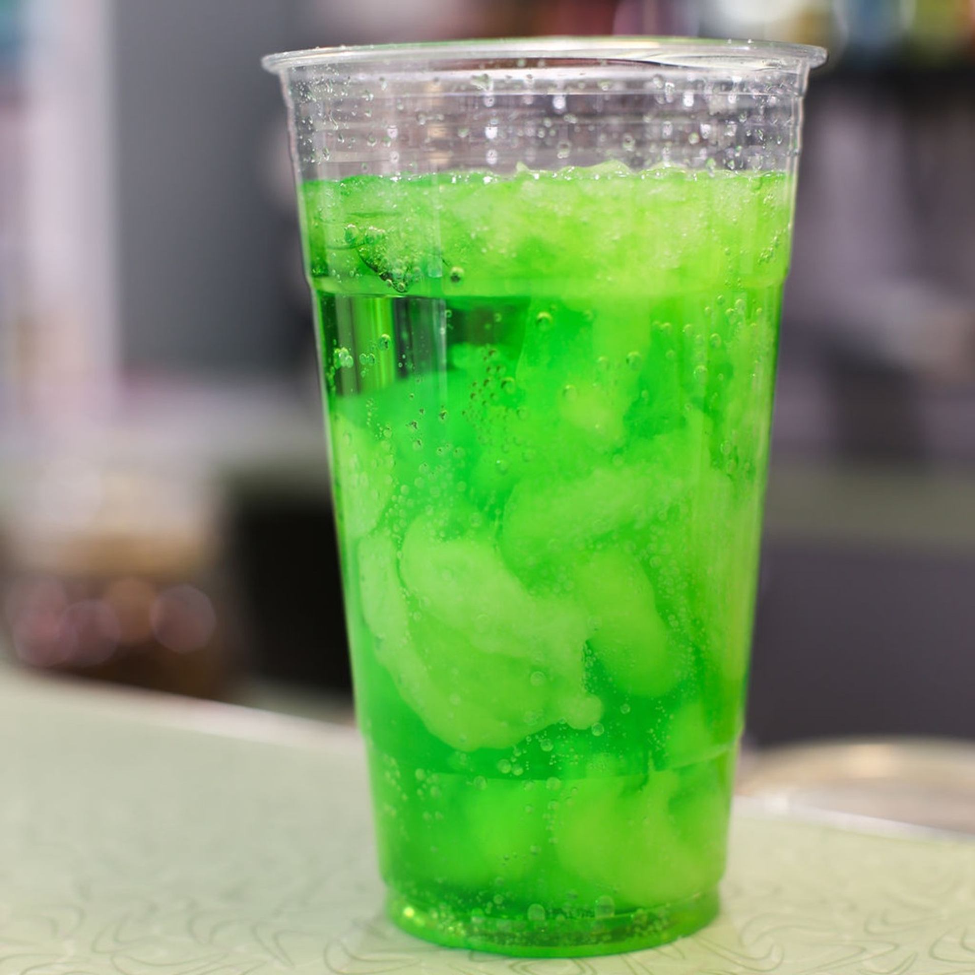 A plastic cup filled with neon green King Craft Soda and ice