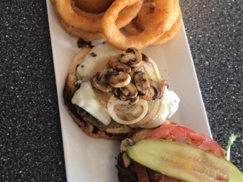 Tray of pastries with mushrooms, wrapped buns, and sliced avocado on a table surface.