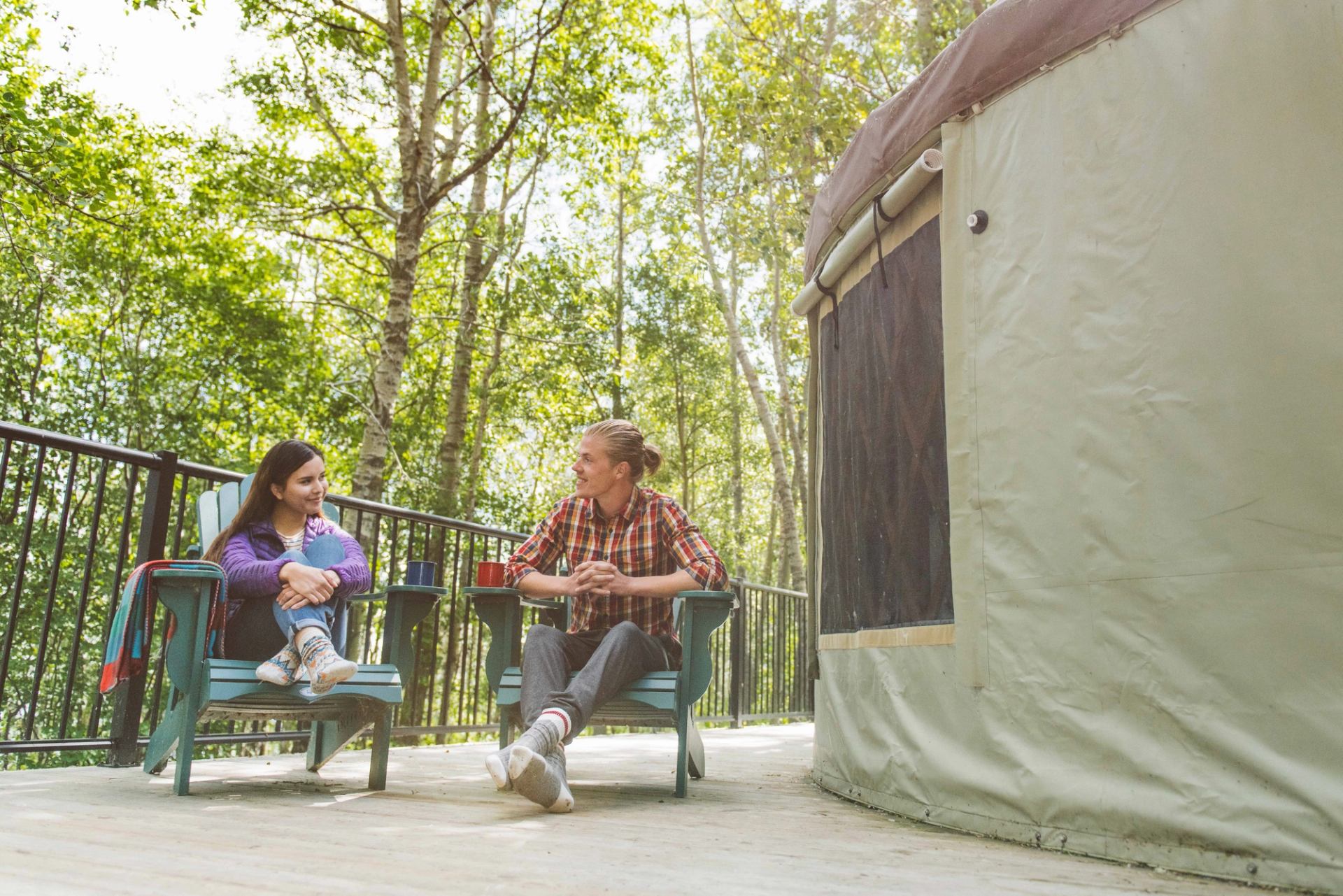 Couple on the deck outside of their Yurt at Pigeon Lake Campground Comfort Camping.